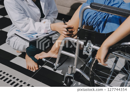 Physiotherapist checking knee of female patient stock Physiotherapist checking knee of female patient stock 127744354