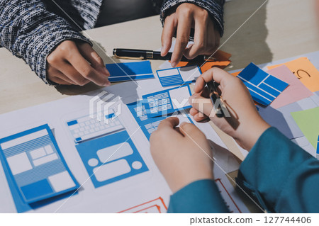 Group of young application developers analyzing uxui mobile app templates during a working meeting 127744406