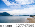 Spectacular view of the Seto Inland Sea overlooking Tatara Bridge and Ikuchijima Island | Blue sky, white clouds, and sandy coastline 127747395