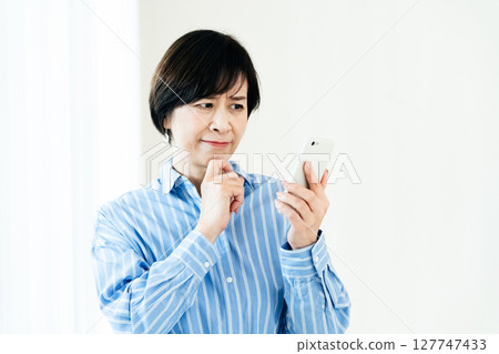 一位操作智能手機的中年婦女 127747433