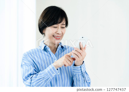 A middle-aged woman who operates a smartphone 127747437