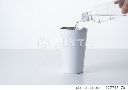 Pour bottled water into a stainless steel tumbler Pour bottled water into a stainless steel tumbler 127748470