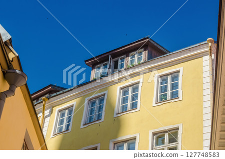 Sunny yellow building facade with dormer windows and clear blue summer sky. High quality photo 127748583