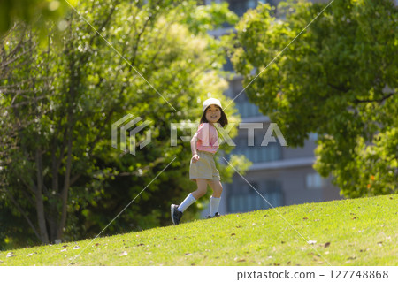 Smiling girl running energetically down the slope in the park 127748868