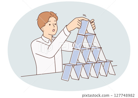 Concentrated man makes pyramid of playing cards symbolizing fragile business structure 127748982