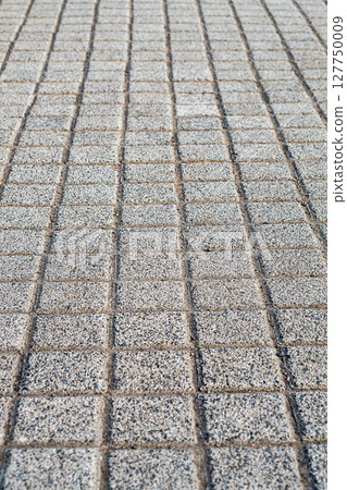 The surface of the street sidewalk paved with square paving stones with a first-person view with a perspective going into the distance. Background for artwork, abstract road ahead symbol 127750009