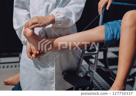 Physiotherapist checking knee of female patient stock Physiotherapist checking knee of female patient stock 127750337