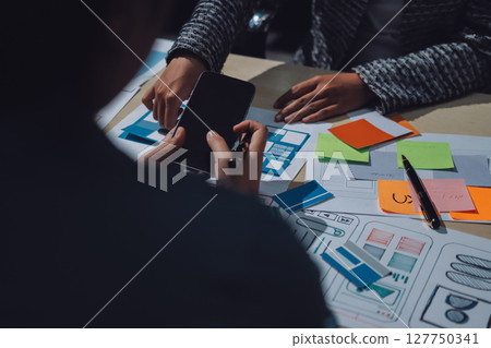 Group of young application developers analyzing uxui mobile app templates during a working meeting 127750341