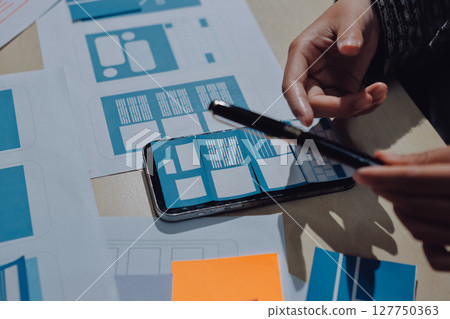 Group of young application developers analyzing uxui mobile app templates during a working meeting 127750363