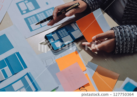 Group of young application developers analyzing uxui mobile app templates during a working meeting 127750364