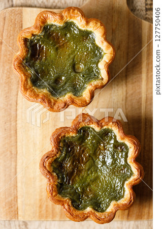 Closeup of Matcha and mochi Portuguese sweet dessert egg tart or Pastel de Nata on wooden board on wooden table. Closeup of Matcha and mochi Portuguese sweet dessert egg tart or Pastel de Nata on wooden board on wooden table. 127750406