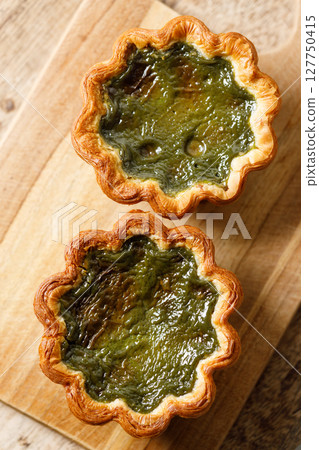 Closeup of Matcha and mochi Portuguese sweet dessert egg tart or Pastel de Nata on wooden board on wooden table. 127750415