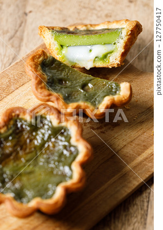 Closeup of Matcha and mochi Portuguese sweet dessert egg tart or Pastel de Nata on wooden board on wooden table. 127750417