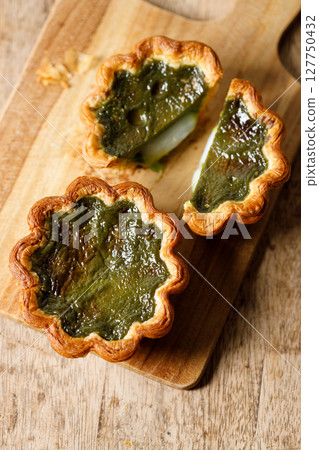 Closeup of Matcha and mochi Portuguese sweet dessert egg tart or Pastel de Nata on wooden board on wooden table. 127750432