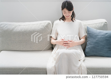 Pregnant woman relaxing on the sofa lifestyle image 127750594