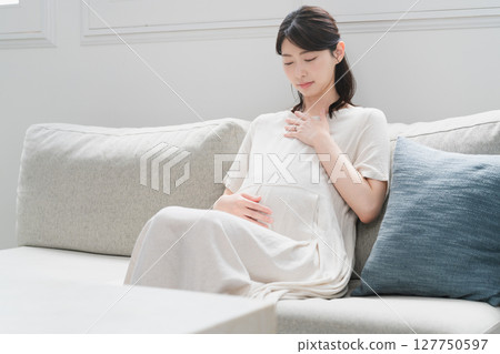 Pregnant woman relaxing on the sofa lifestyle image 127750597