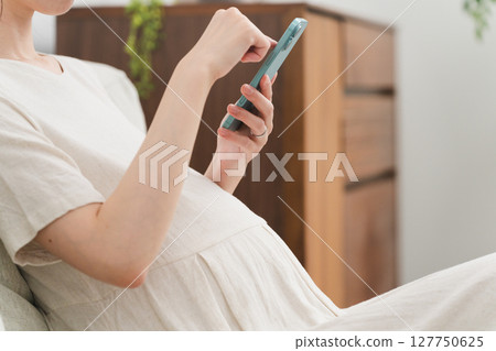 孕婦在沙發上操作智慧型手機的生活風格影像 127750625