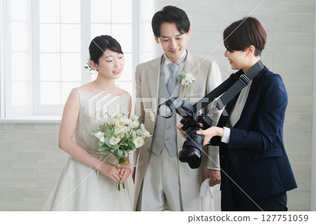 Bride and groom checking the photos taken by the photographer Wedding image Bride and groom checking the photos taken by the photographer Wedding image 127751059