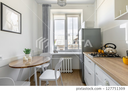 Bright Kitchen with Dining Table, Window and Wooden Countertop 127751309