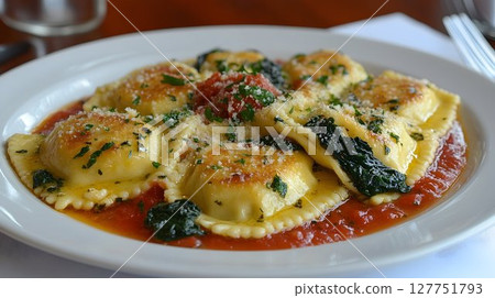 Delicious spinach ravioli served in tomato sauce on white plate in restaurant 127751793