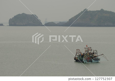 Fishing boat and limestone cliff. 127752307