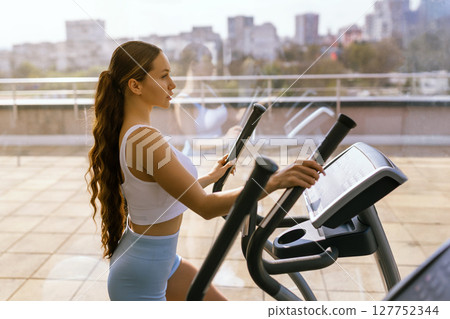attractive girl doing cardio workout in fitness center or gym, selective focus - health and fitness concept attractive girl doing cardio workout in fitness center or gym, selective focus - health and fitness concept 127752344