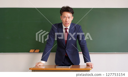 A male teacher speaking with a serious expression 127753154
