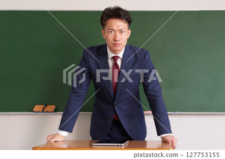 一位穿著西裝的男老師正在看著一件嚴肅的事情 一位穿著西裝的男老師正在看著一件嚴肅的事情 127753155