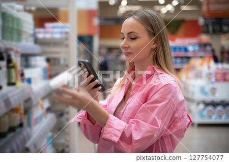 Customer using smartphone scanning products in supermarket 127754077