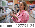 Customer using smartphone scanning product in supermarket 127754124