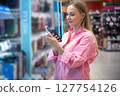 Customer choosing toothbrush in supermarket hygiene products aisle 127754126