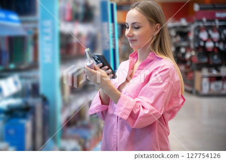 Customer choosing toothbrush in supermarket hygiene products aisle 127754126