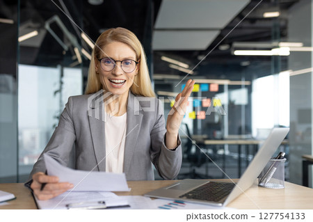 A professional woman, wearing glasses, expresses herself during a meeting or a presentation. 127754133