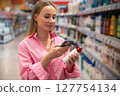 Customer scanning product with smartphone in supermarket 127754134