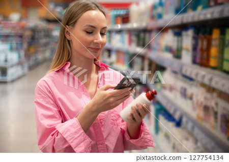 Customer scanning product with smartphone in supermarket Customer scanning product with smartphone in supermarket 127754134