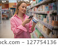 Woman choosing medicine in pharmacy scanning products with smartphone 127754136