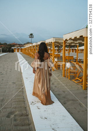 Woman Walking Alone on a Sandy Beach Pathway 127754138