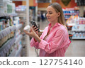Customer using smartphone scanning products in supermarket 127754140