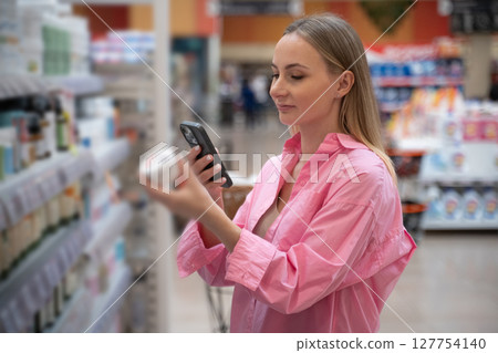 Customer using smartphone scanning products in supermarket 127754140
