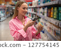 Customer scanning product barcode with smartphone in supermarket 127754145