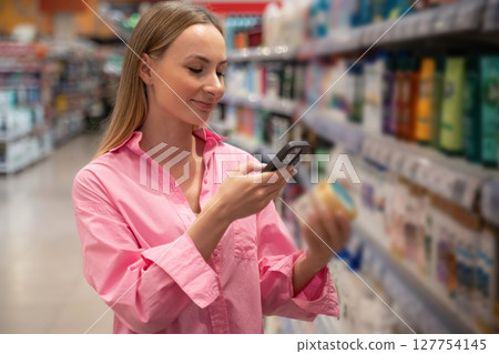 Customer scanning product barcode with smartphone in supermarket Customer scanning product barcode with smartphone in supermarket 127754145
