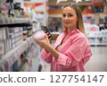 Woman using smartphone scanning products on supermarket shelf 127754147