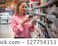 Customer using smartphone scanning product in supermarket or pharmacy 127754151