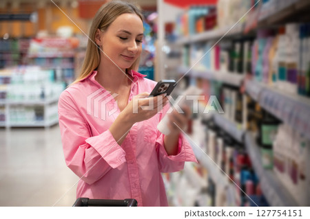 Customer using smartphone scanning product in supermarket or pharmacy 127754151