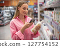 Customer using smartphone scanning product in supermarket 127754152