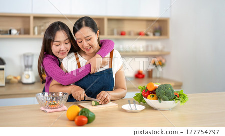 Cooking Together. Women sharing a loving moment while preparing a healthy meal in the kitchen. Cooking Together. Women sharing a loving moment while preparing a healthy meal in the kitchen. 127754797
