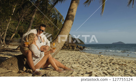 Loving couple in white dress and sunglasses, near palm tree, rel 127755124