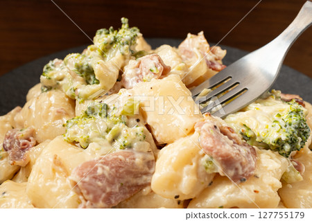 Cream Tteokbokki Korean Rice Cake with Bacon and Broccoli on Black Plate 127755179