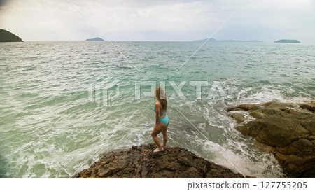 Woman chill relax resting on rock of sea reef stone, stormy cloudy ocean. Woman in swimsuit dress tunic. Concept rest tropical outdoor tourism Woman chill relax resting on rock of sea reef stone, stormy cloudy ocean. Woman in swimsuit dress tunic. Concept rest tropical outdoor tourism 127755205