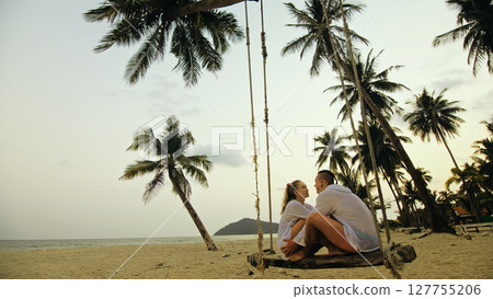 Loving couple on the swing on tropical beach. Woman and man in w 127755206